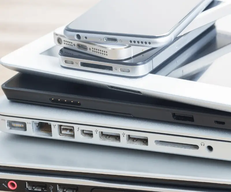 Image of a stack of laptops, Ipads, and Iphones