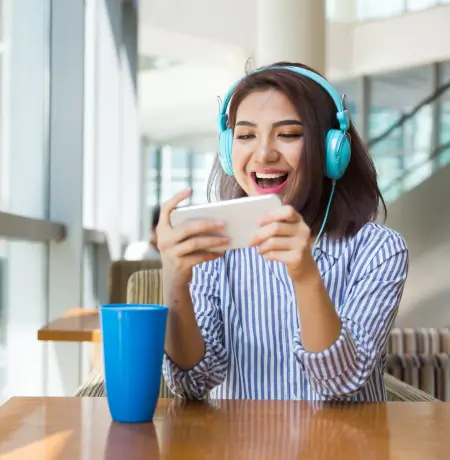 Image of a woman sitting at a table playing a game on her cellphone