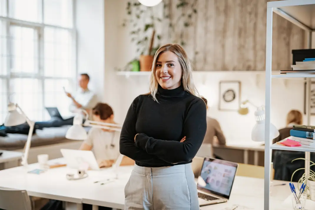 Image of a woman standing and smiling in an office workspace