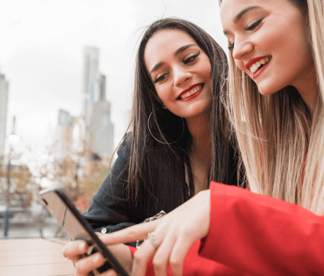 Image of two women in city looking at cell phone