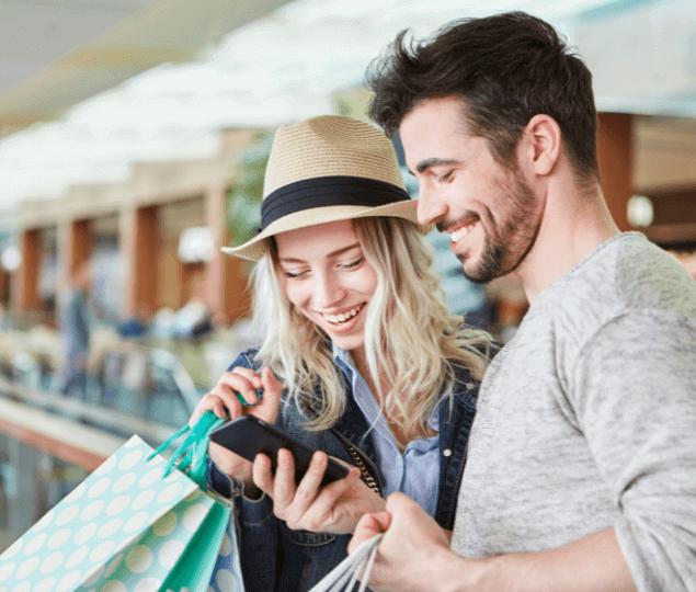 Image of a man and a woman looking at a phone and laughing