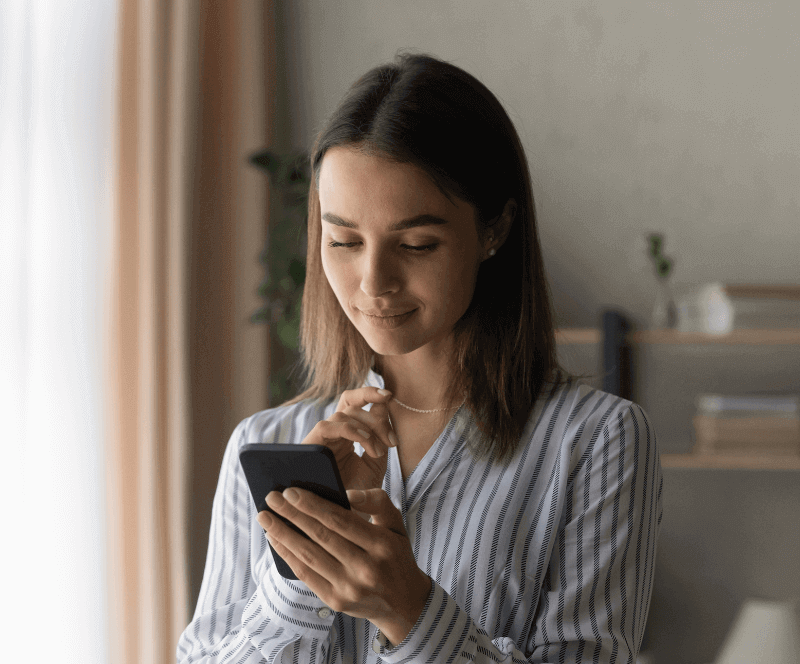 Image of a woman smiling at her phone